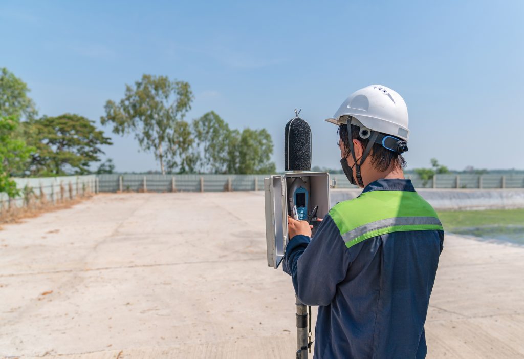 An environmental officer is setting up a sound level meter for monitoring.