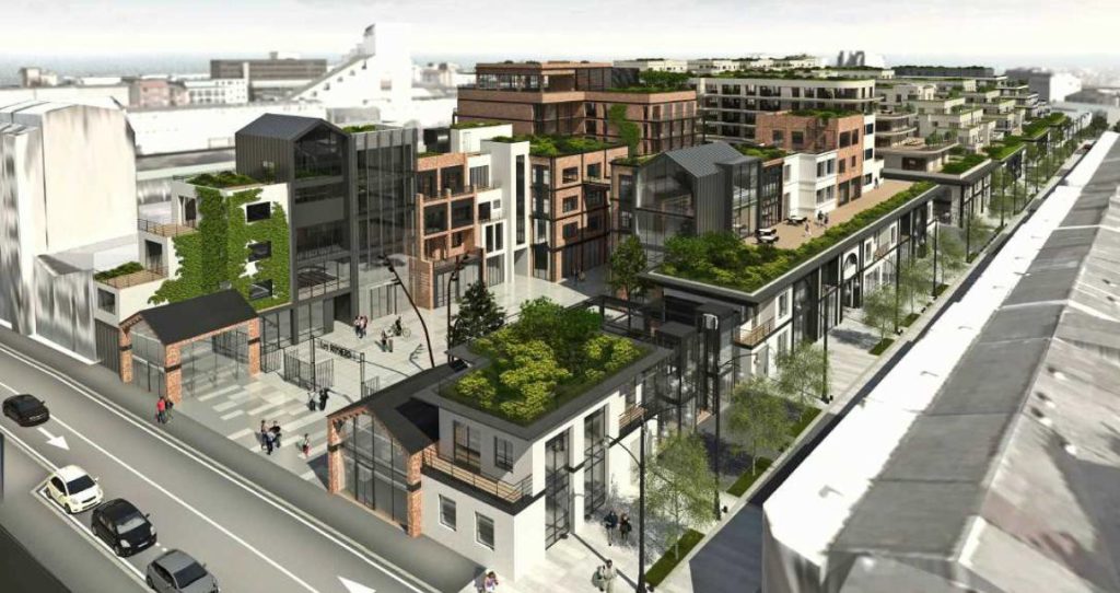 Rendu 3D en perspective aérienne d'un programme hôtelier et de logements en milieu urbain dense, avec toitures végétalisées, commerces en rez-de-chaussée et voie ferrée en limite de parcelle